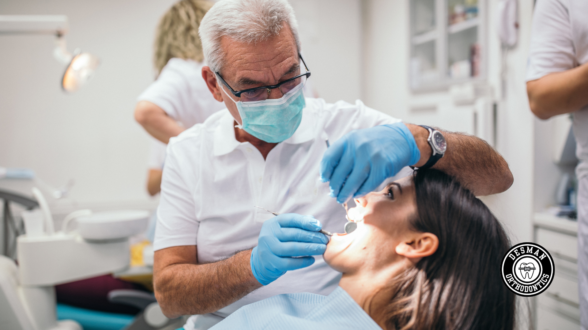 Dentist examining a patient in a clinic, wearing blue gloves and a mask.