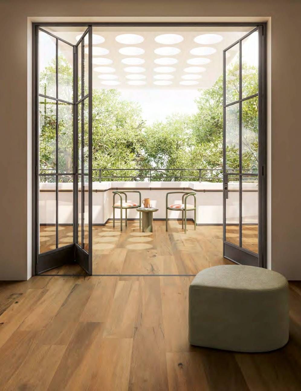 Luminoso soggiorno che si apre su un balcone con porte finestre, pavimento in legno e alberi verdi all'esterno.