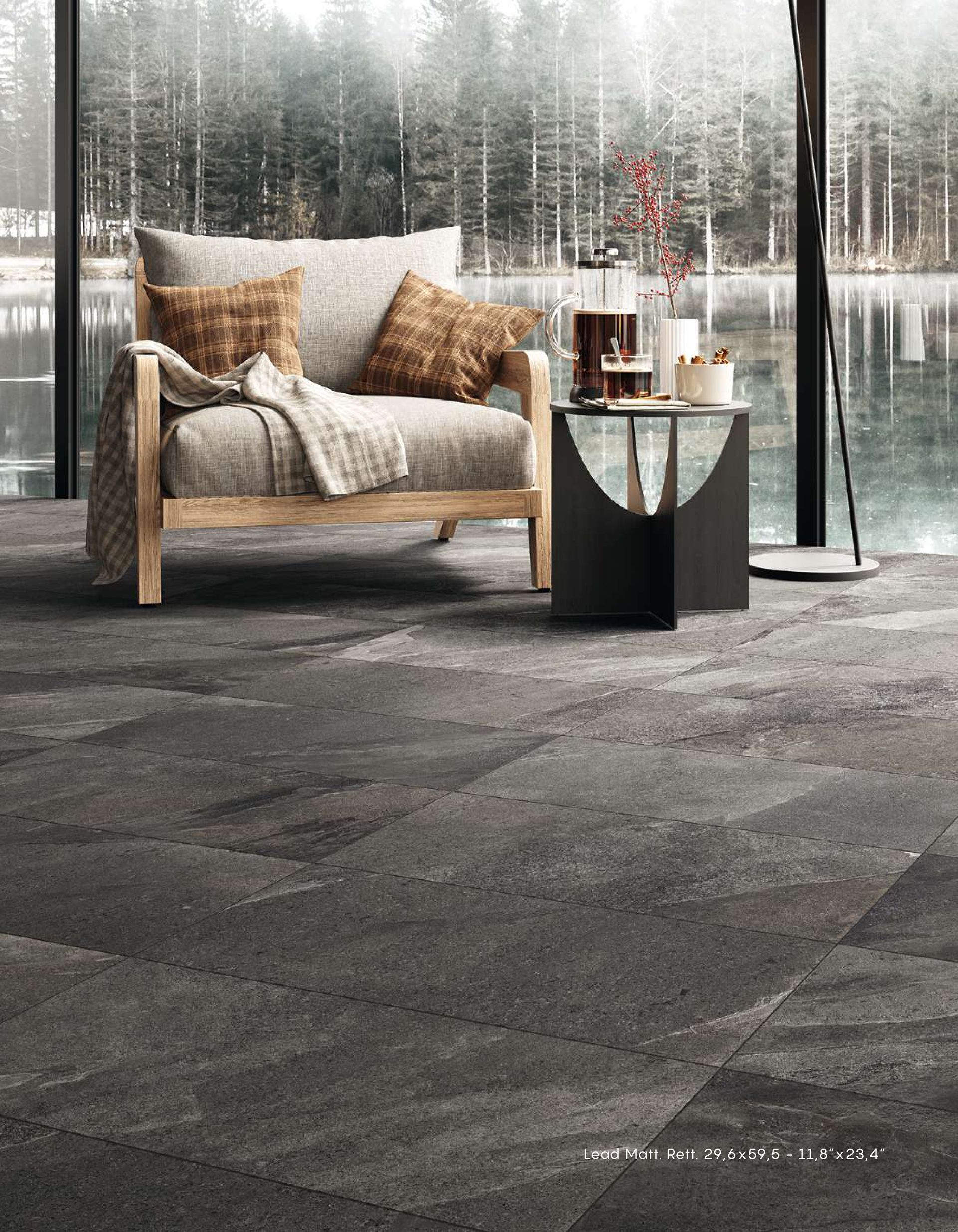 Comoda poltrona relax accanto a una finestra con tappeto dalla texture particolare, tavolino laterale e vista sulla foresta innevata all'esterno.