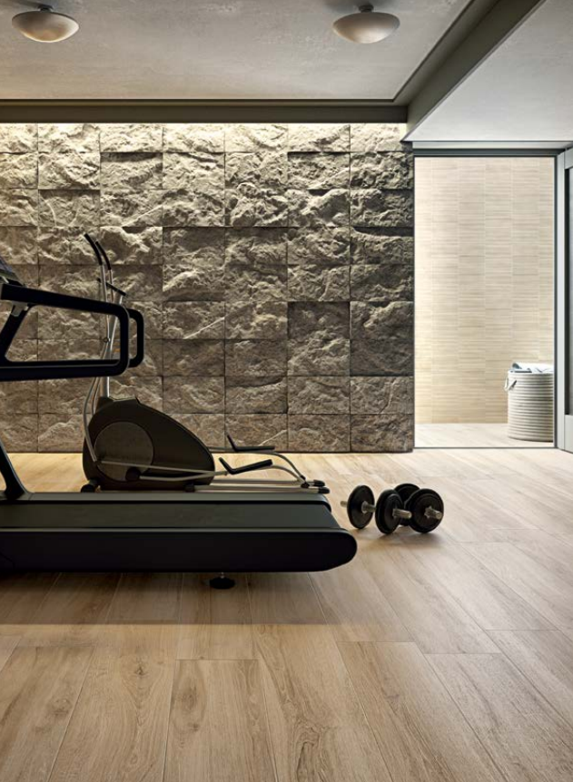 Palestra moderna con tapis roulant, manubri e parete decorativa in pietra in un ambiente minimalista.