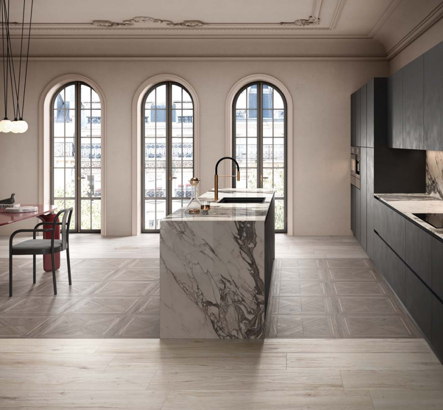 Cucina moderna con isola in marmo, mobili scuri e alte finestre ad arco.