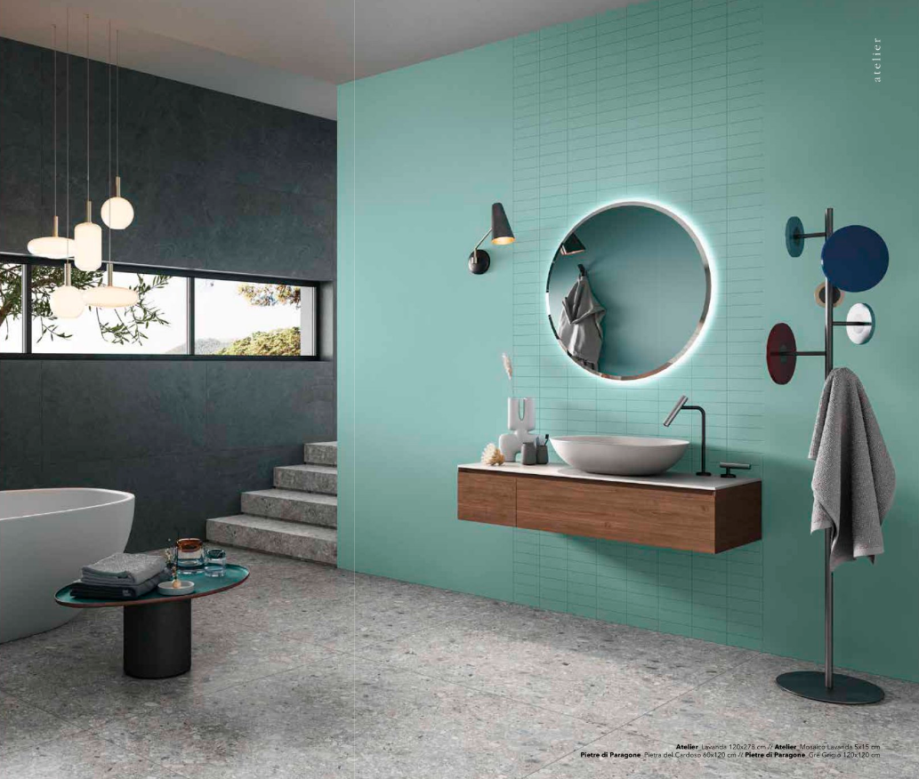 Bagno moderno con parete color acquamarina, specchio rotondo, lavabo in legno e scala sullo sfondo.