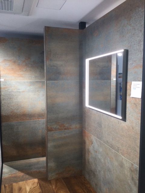 Bagno moderno con pareti in pietra, box doccia in vetro e specchio retroilluminato.