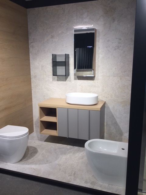 Bagno moderno con WC, lavabo con mobiletto, specchio e bidet in tonalità neutre.