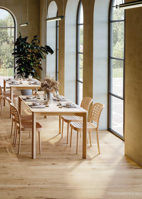 Luminosa sala da pranzo con tavolo apparecchiato, sedie in legno, finestre ad arco e pavimento in legno chiaro.