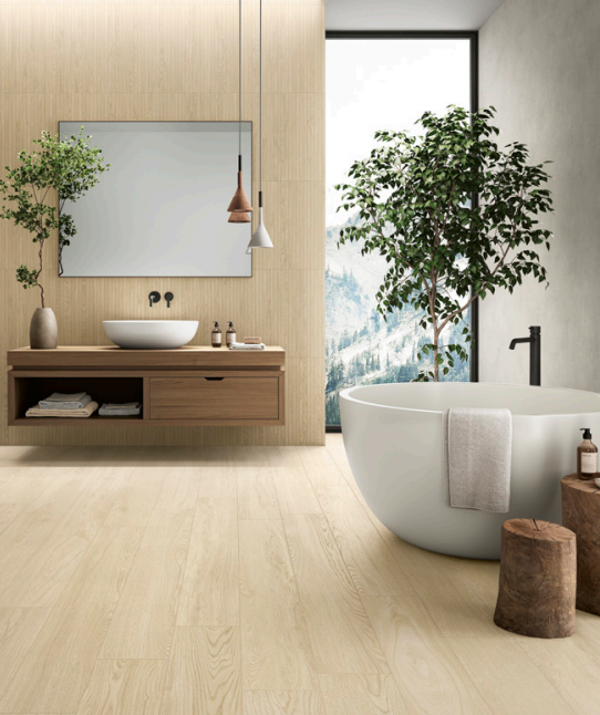Bagno moderno con mobile lavabo in legno, vasca rotonda, ampia finestra e pianta da interno, in delicate tonalità neutre.