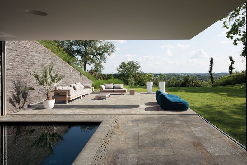 Patio moderno con piscina, lettini prendisole e giardino erboso con vista su un paesaggio suggestivo.