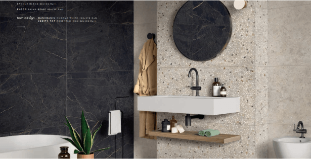 Bagno moderno con parete nera, piastrelle in pietra, specchio rotondo, lavabo sospeso e piccola pianta in vaso.