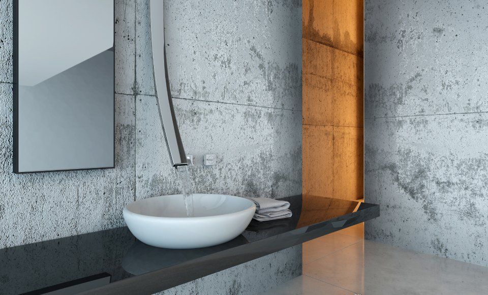 Lavabo da bagno moderno con rubinetto a parete, piano d'appoggio nero, specchio e illuminazione calda.
