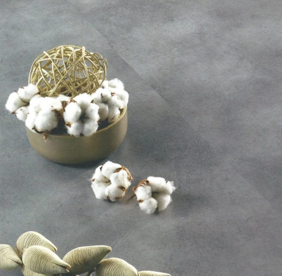 Capsule di cotone in una ciotola dorata con una sfera decorativa dorata su uno sfondo di tessuto grigio.