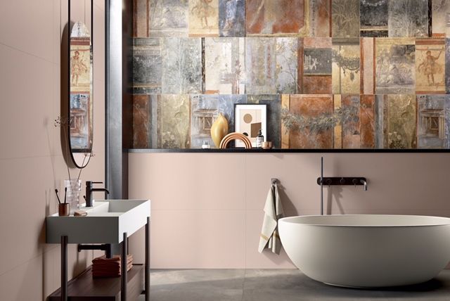 Bagno moderno con parete rivestita in piastrelle a mosaico, vasca ovale e mobile lavabo bianco con specchio.