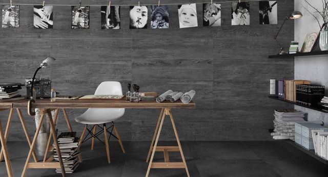 Cucina moderna con tavolo in legno, sedia bianca, quadri grigi alle pareti e scaffali con piatti e libri.