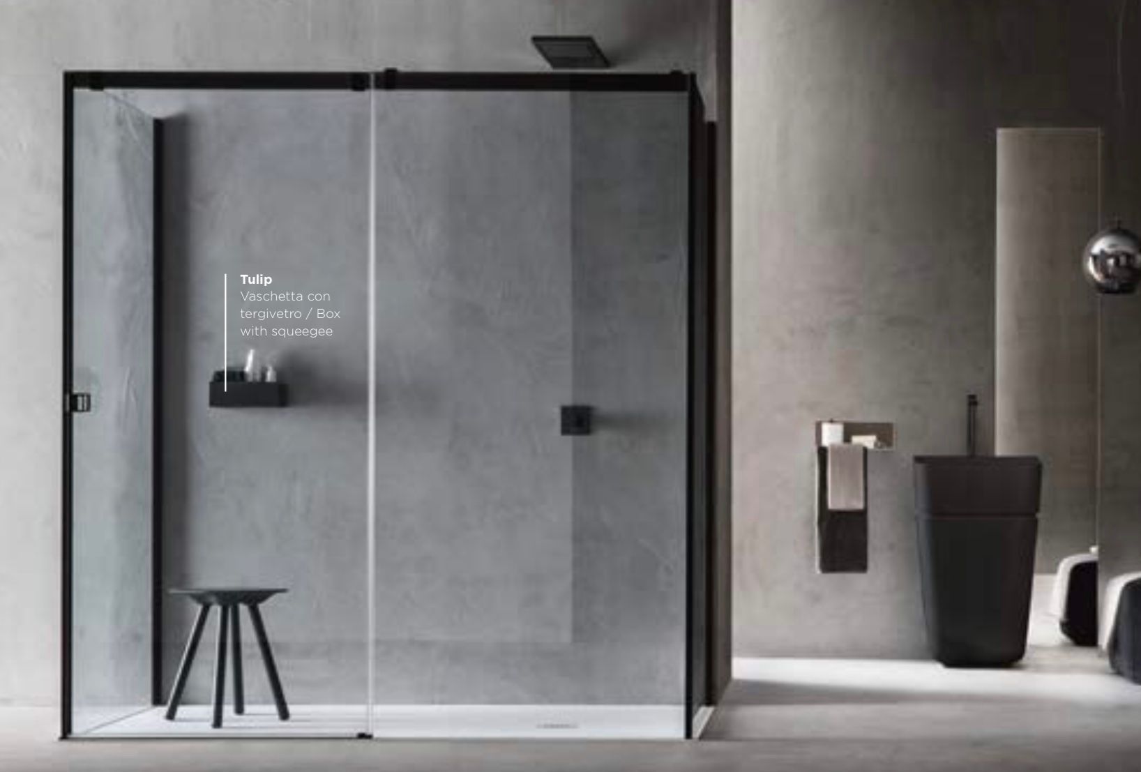 Bagno moderno di colore grigio con box doccia in vetro, portarotolo a parete, sgabello nero e cestino per i rifiuti.