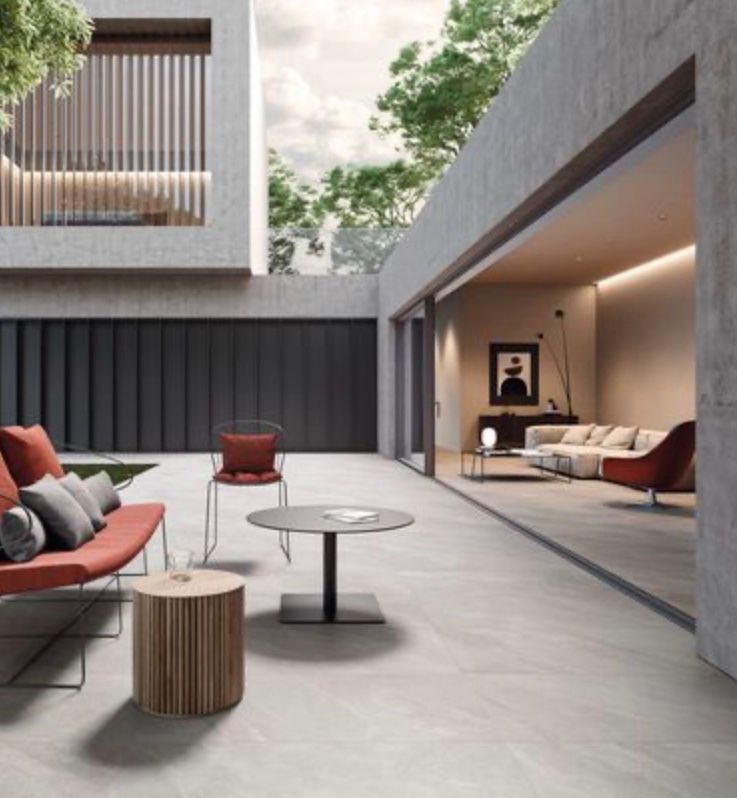 Moderno patio in cemento con sedute rosse e beige e zona relax coperta.