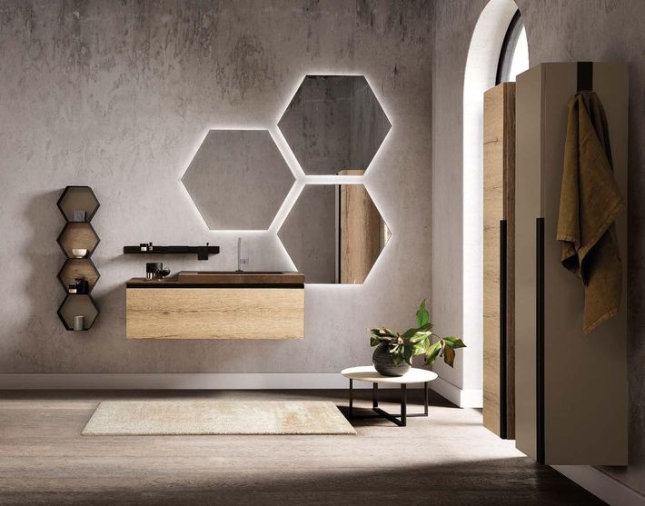 Bagno moderno con specchi esagonali, mobile lavabo sospeso, tappeto beige e portasciugamani vicino a una finestra ad arco.