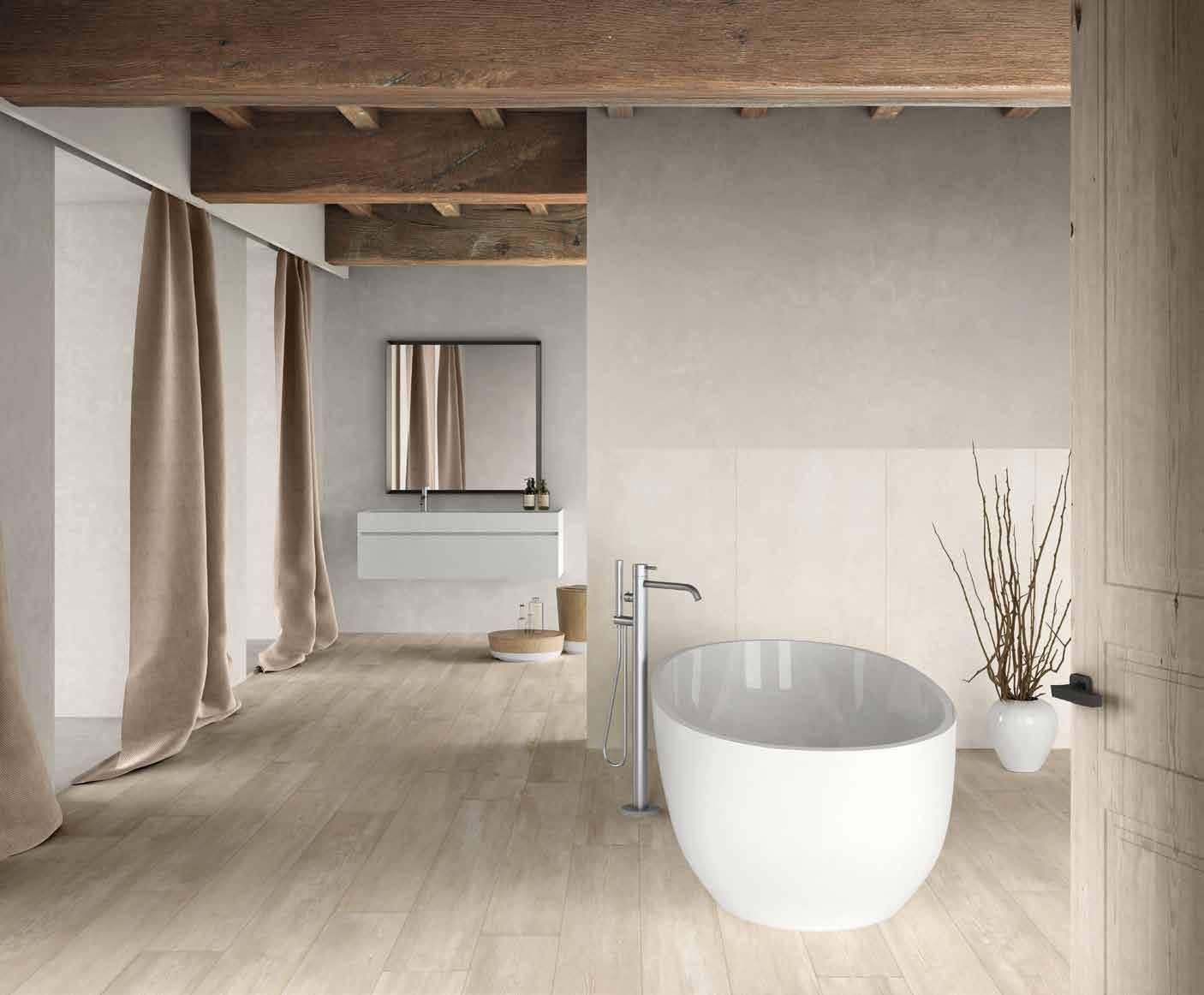 Bagno minimalista con vasca freestanding bianca, soffitto in legno e finiture in pietra chiara.