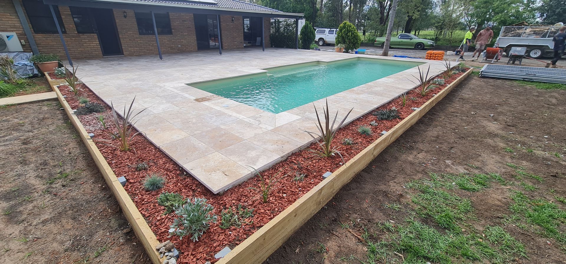 Swimming Pool Surrounded by a Stone Patio and Garden Beds — Newcorp Pools In Moore Creek, NSW