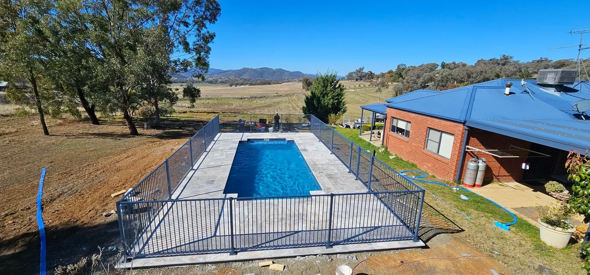 An Outdoor Swimming Pool Surrounded by a Fence and Deck — Newcorp Pools In Gunnedah, NSW