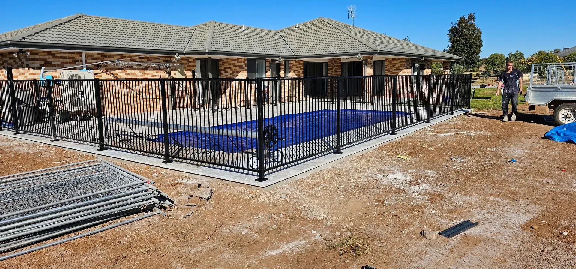 Black Metal Fenced Pool Near a House, With a Person Standing Beside a Truck — Newcorp Pools In Gunnedah, NSW