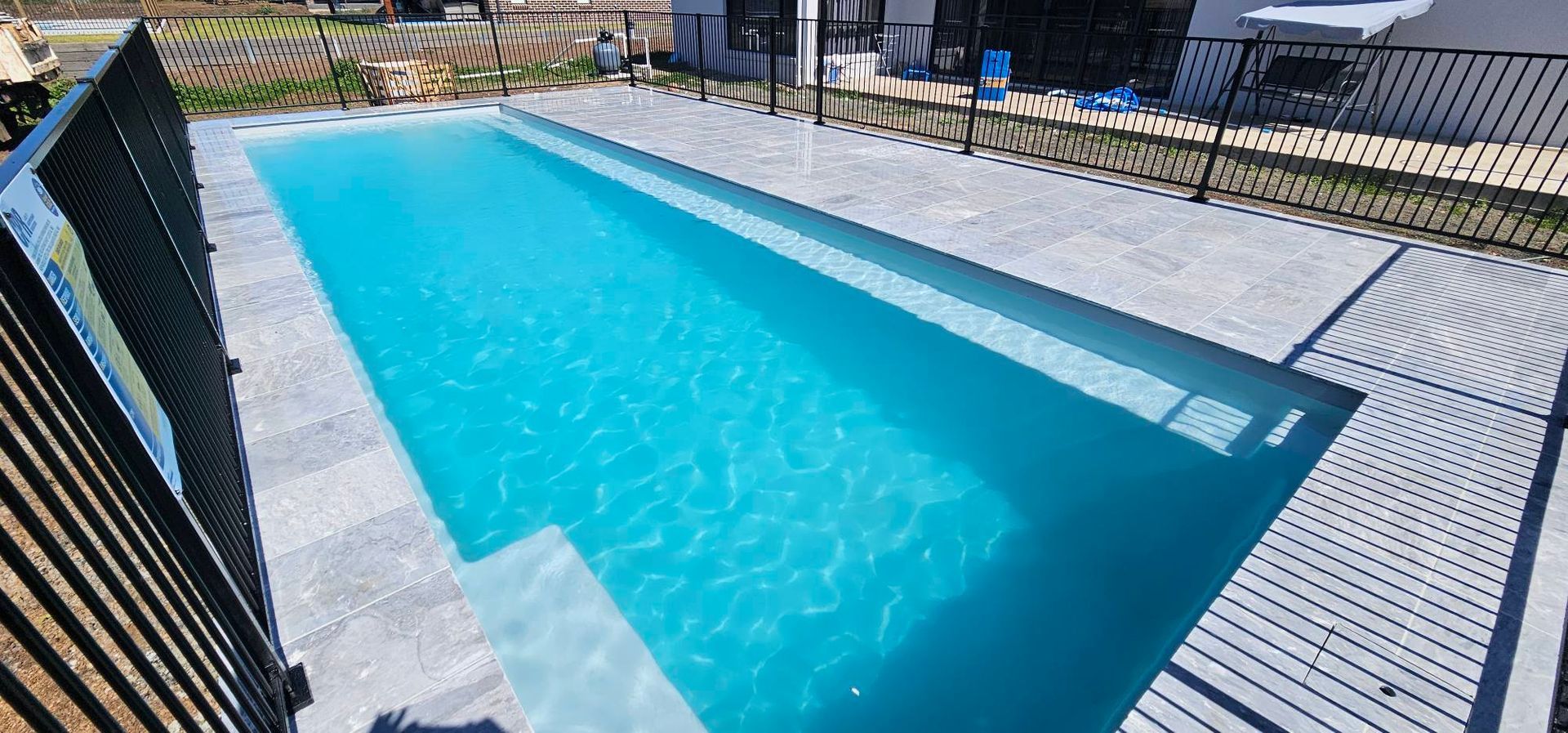 A Rectangular Blue Swimming Pool Surrounded by a Light-coloured Patio — Newcorp Pools In Moore Creek, NSW