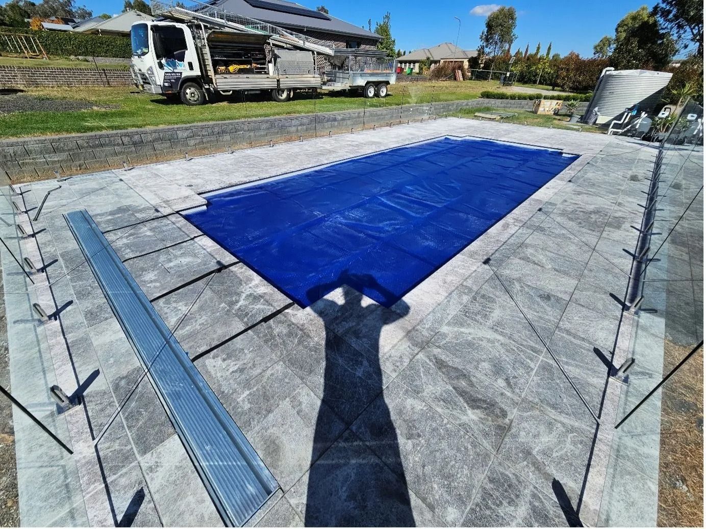 Blue Pool Cover on a Rectangular Pool Surrounded by Grey Pavers — Newcorp Pools In Moore Creek, NSW