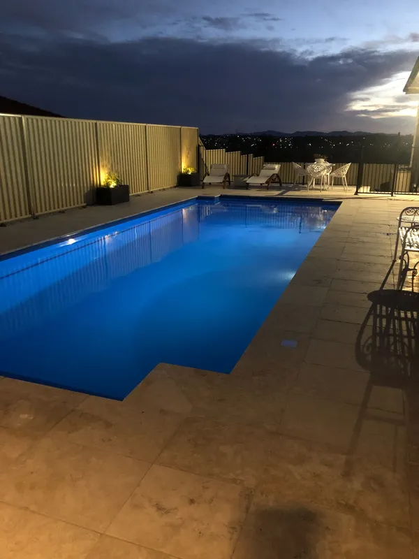 Pool at Dusk With Blue Water, Surrounded by Light-coloured Paving — Newcorp Pools In Moore Creek, NSW
