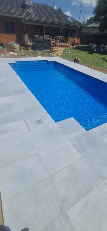 Rectangular Pool With Blue Water Surrounded by Light Grey Pavers — Newcorp Pools In Moore Creek, NSW