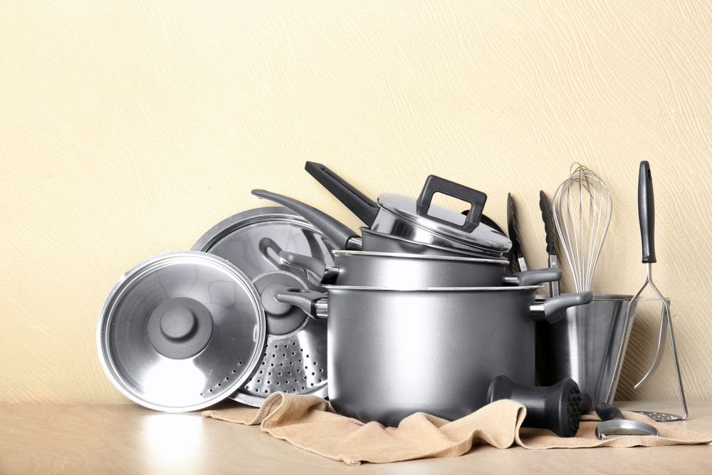 A bunch of pots and pans are sitting on a wooden table.