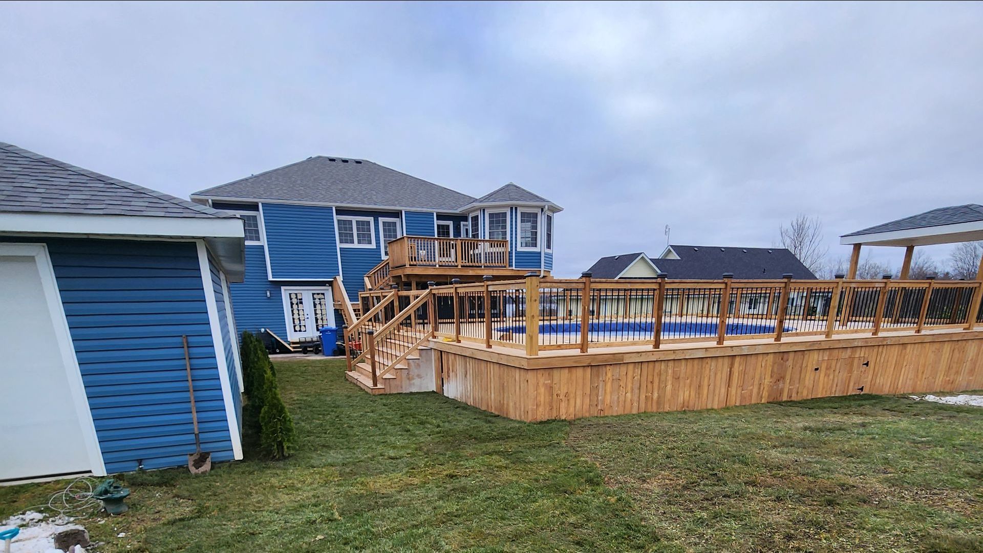 A large blue house with a wooden deck in front of it.