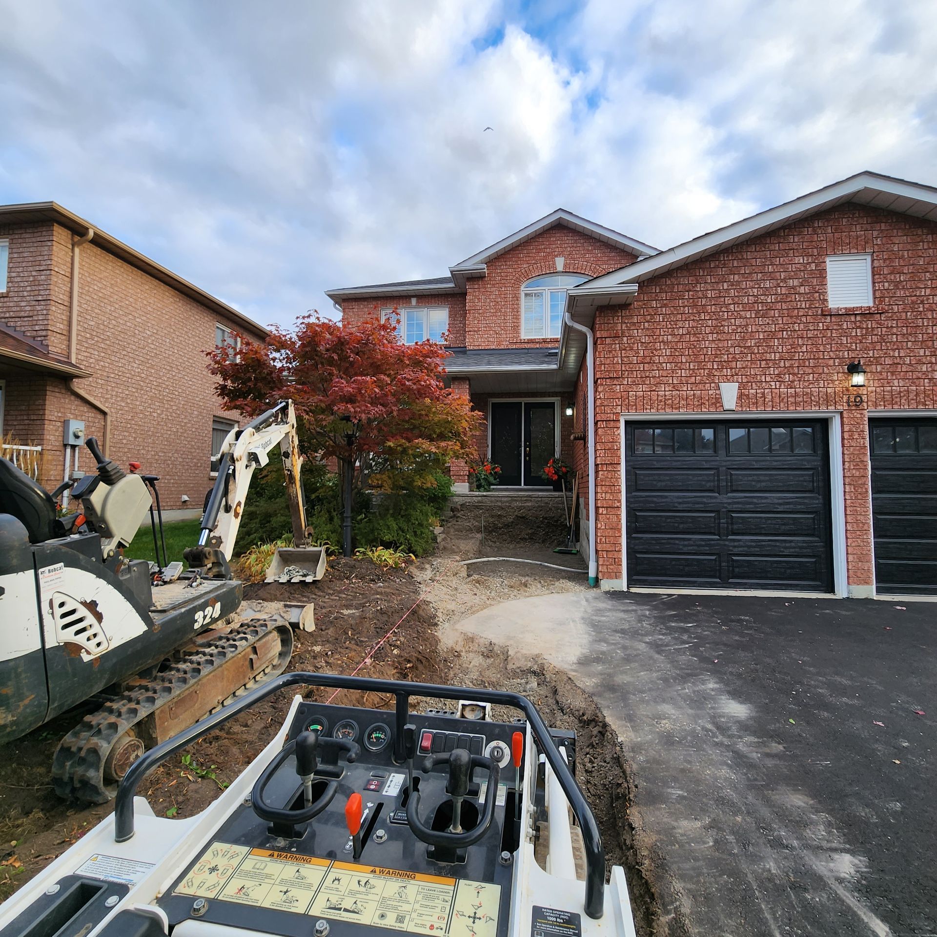 A bobcat is parked in front of a brick house