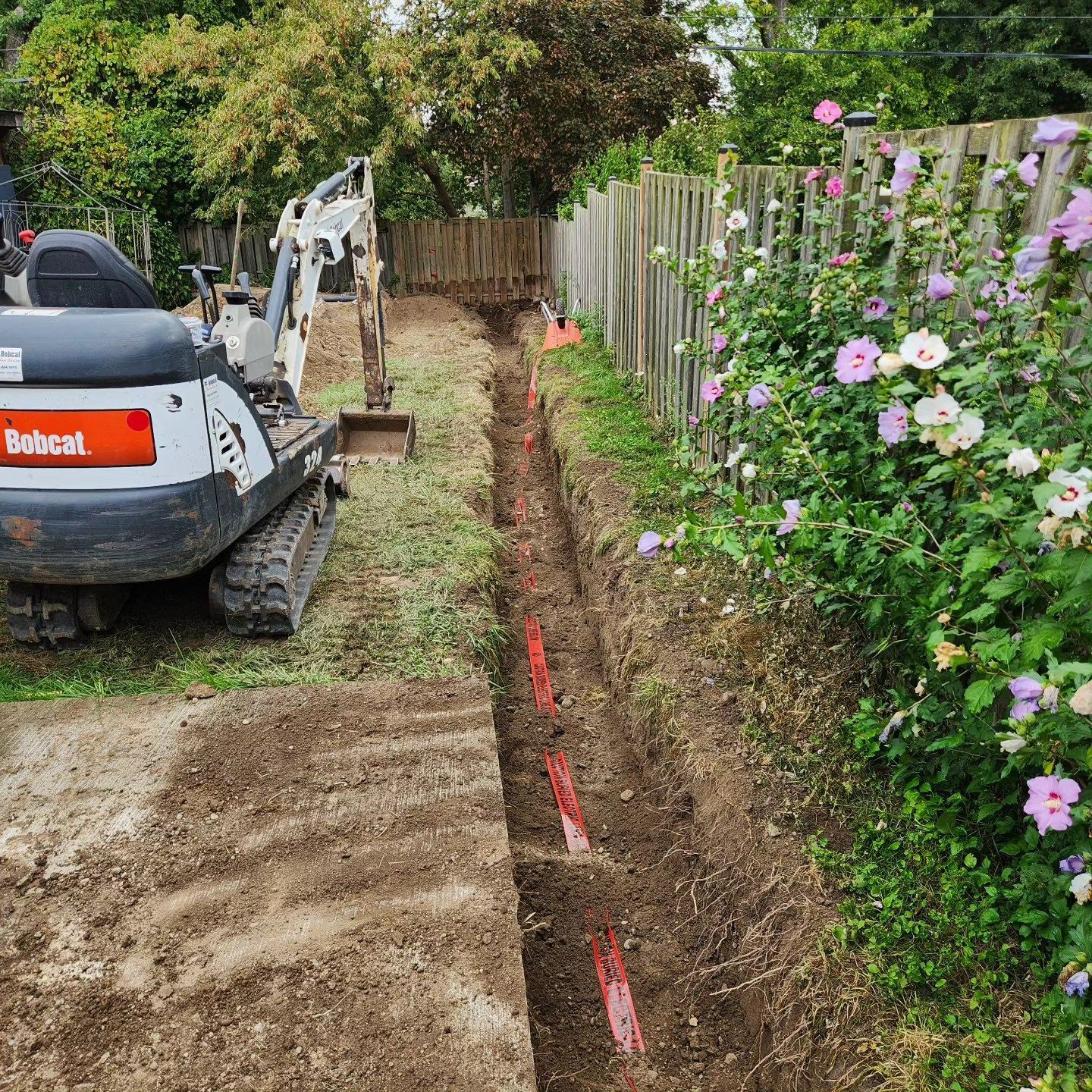 Two pipes are being installed in a trench in the dirt.