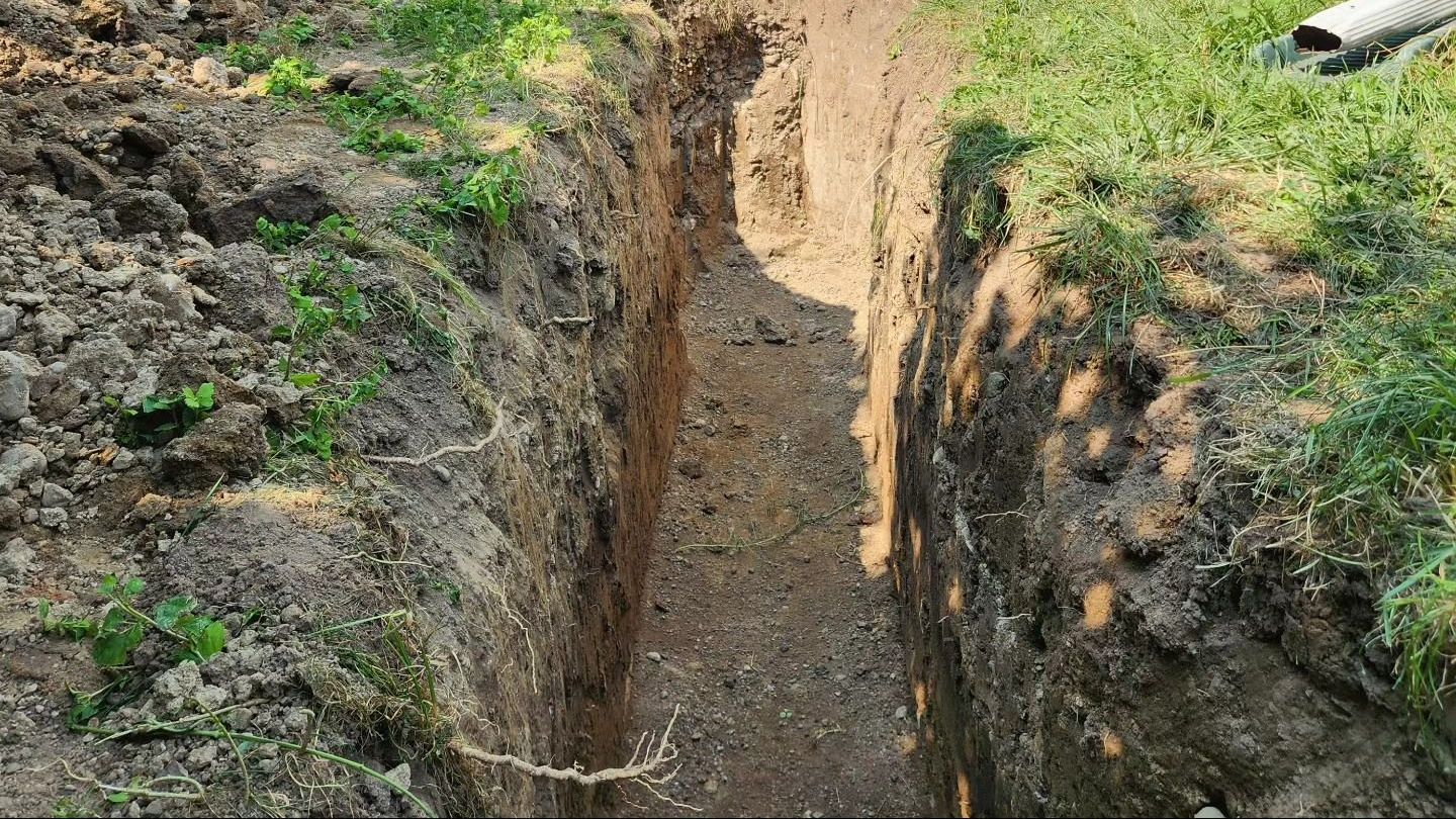 A large hole in the ground in front of a house