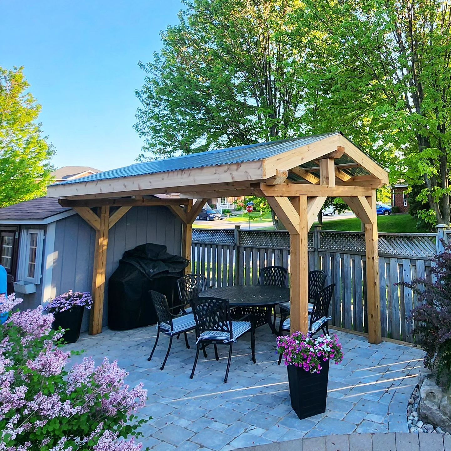 A wooden gazebo with a table and chairs underneath it
