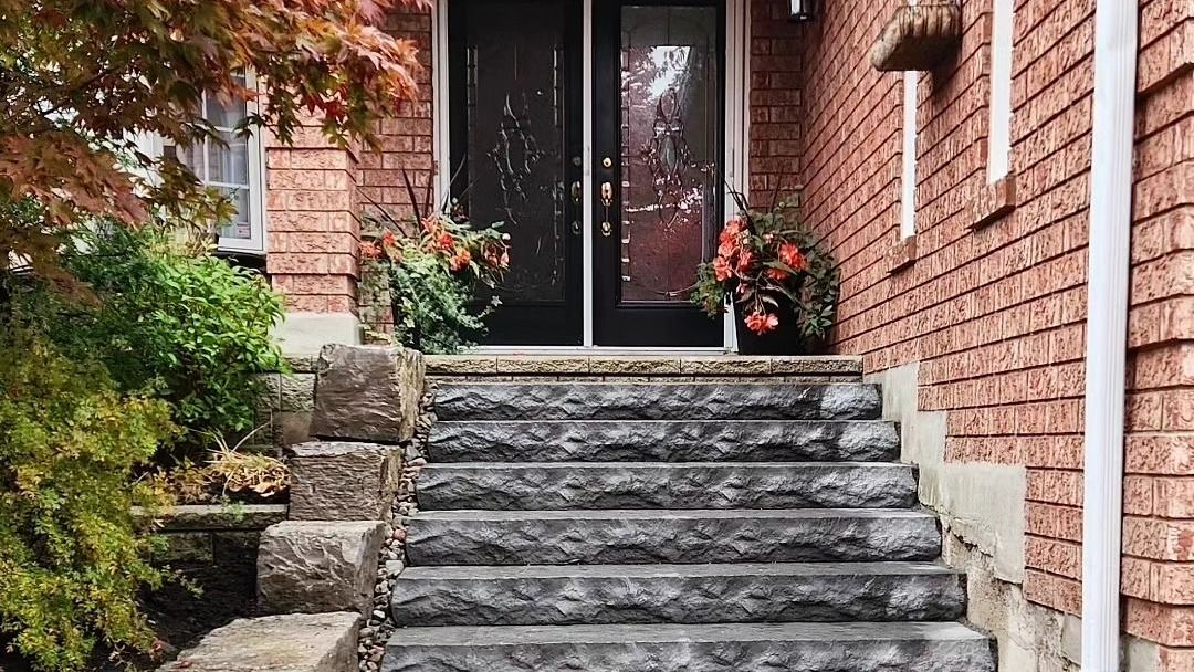 There are stairs leading up to the front door of a brick house.
