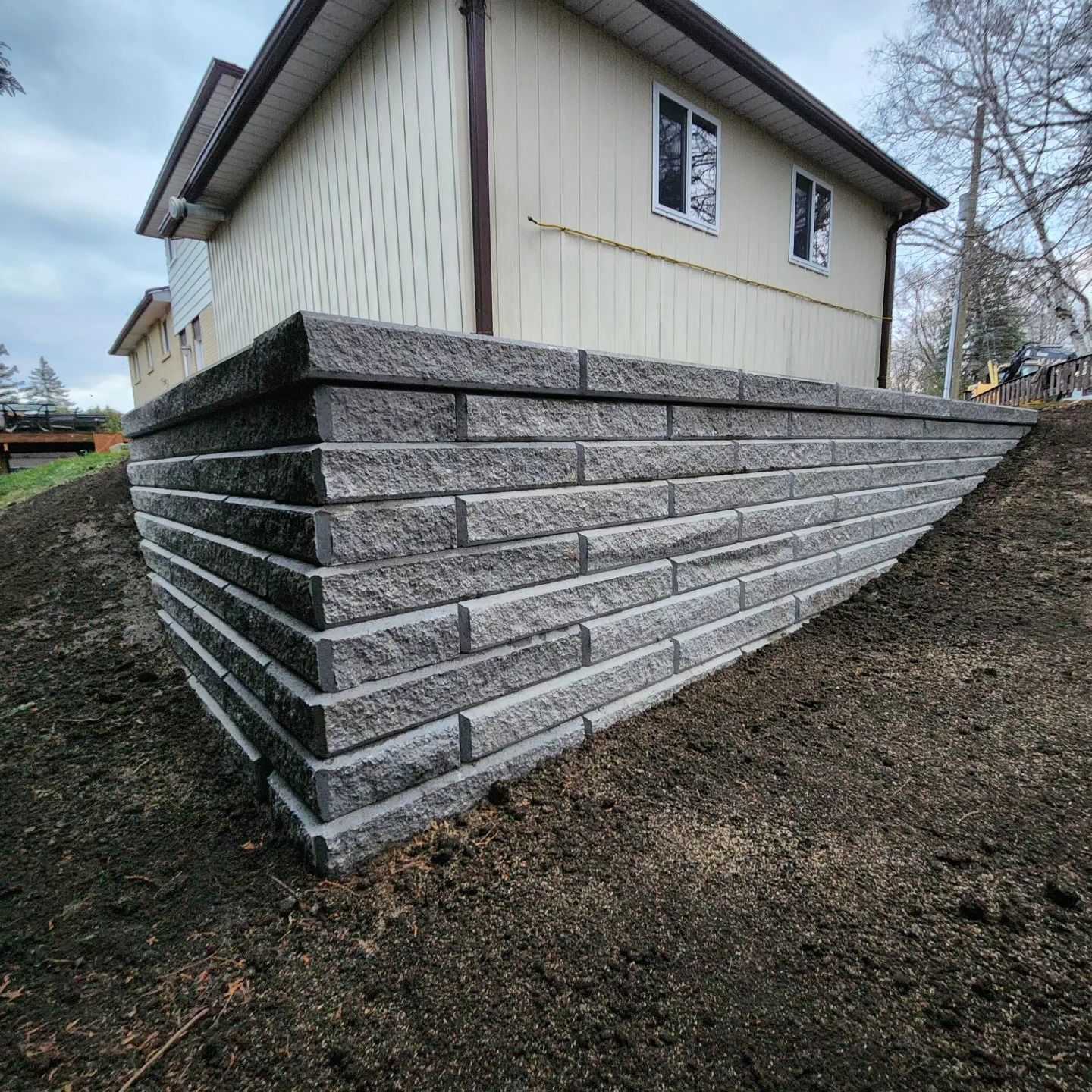 A house with a retaining wall on the side of it.