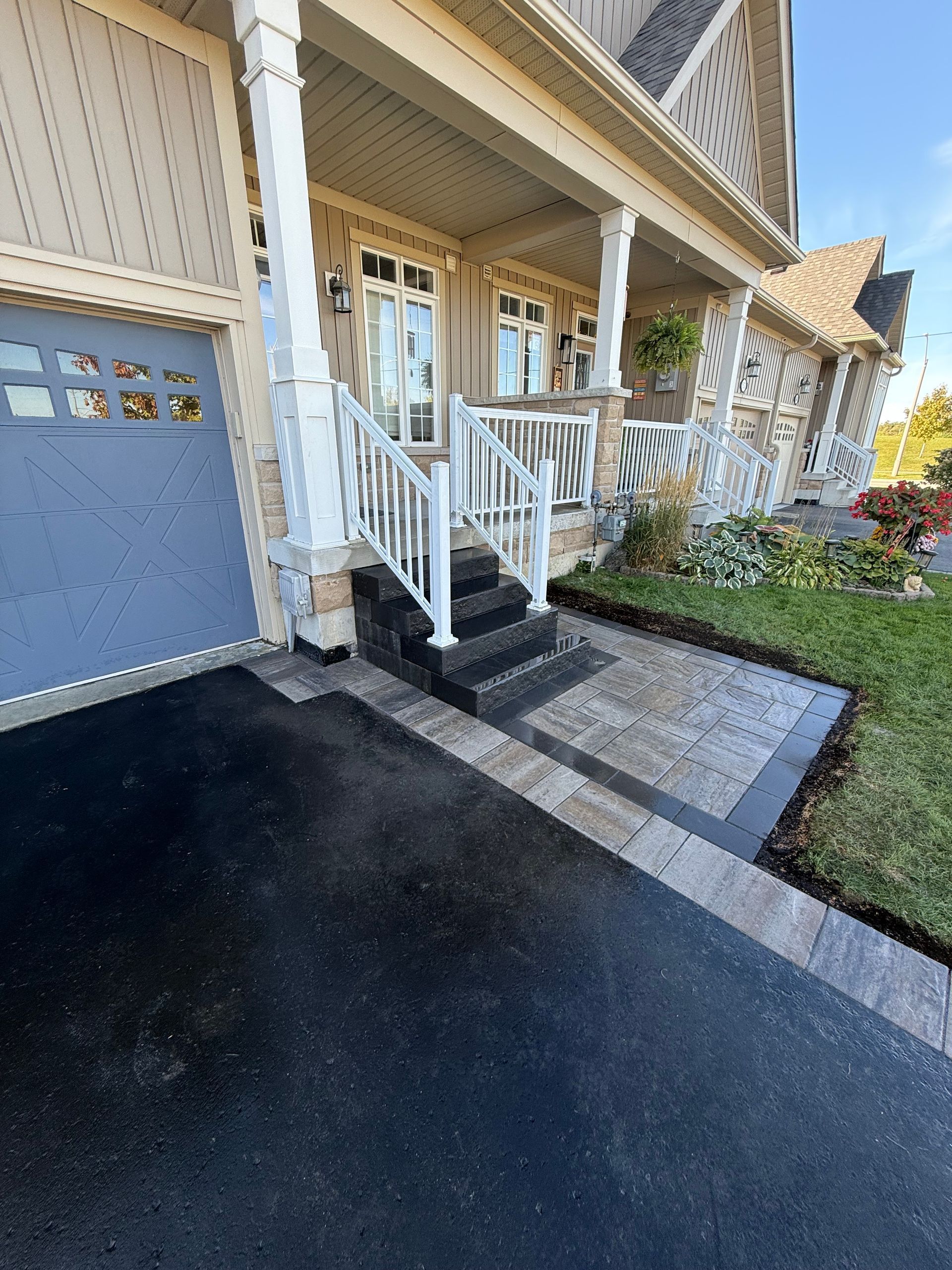 Exterior of house with steps and porch, paved walkway, and dark driveway.