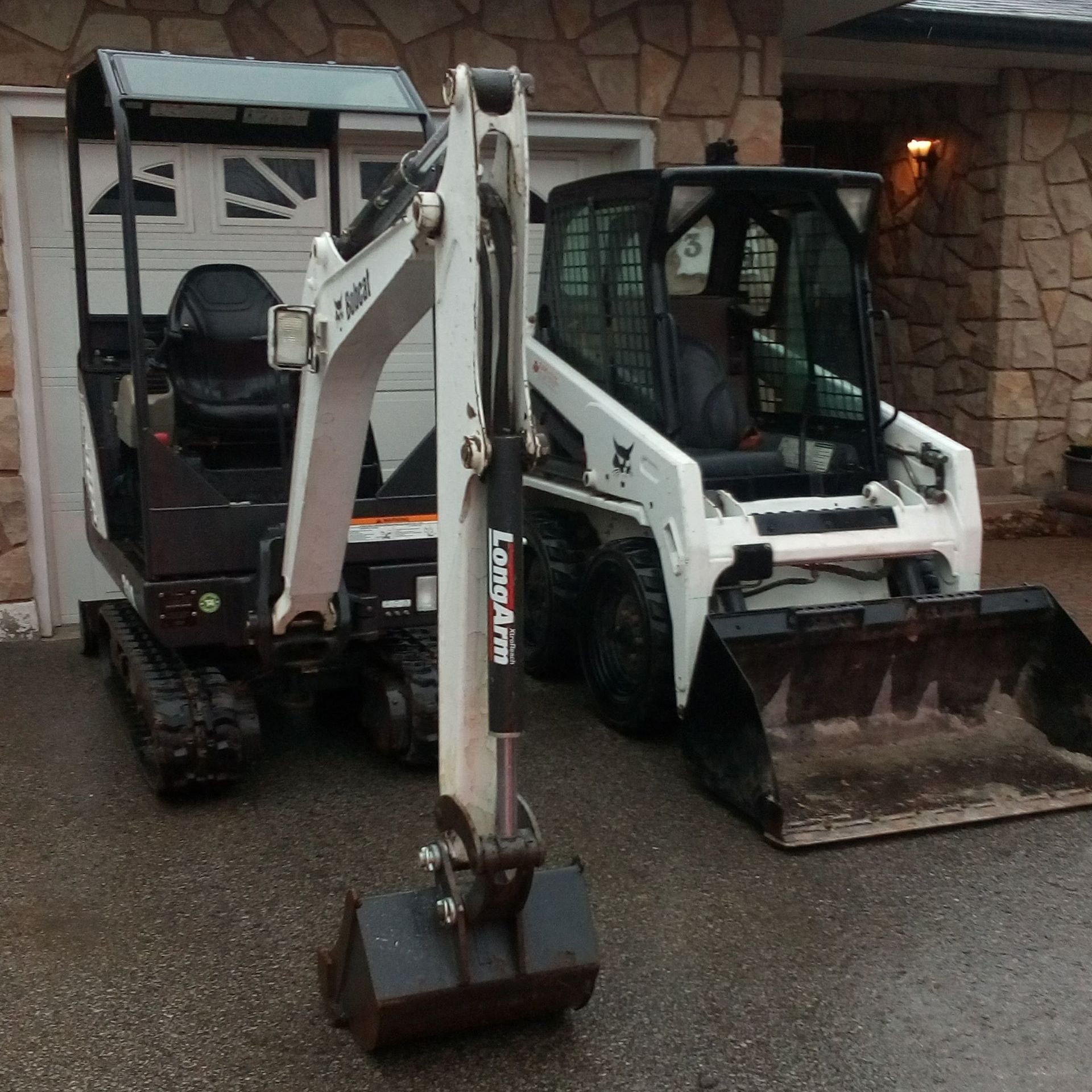 Two bobcat tractors are parked next to each other