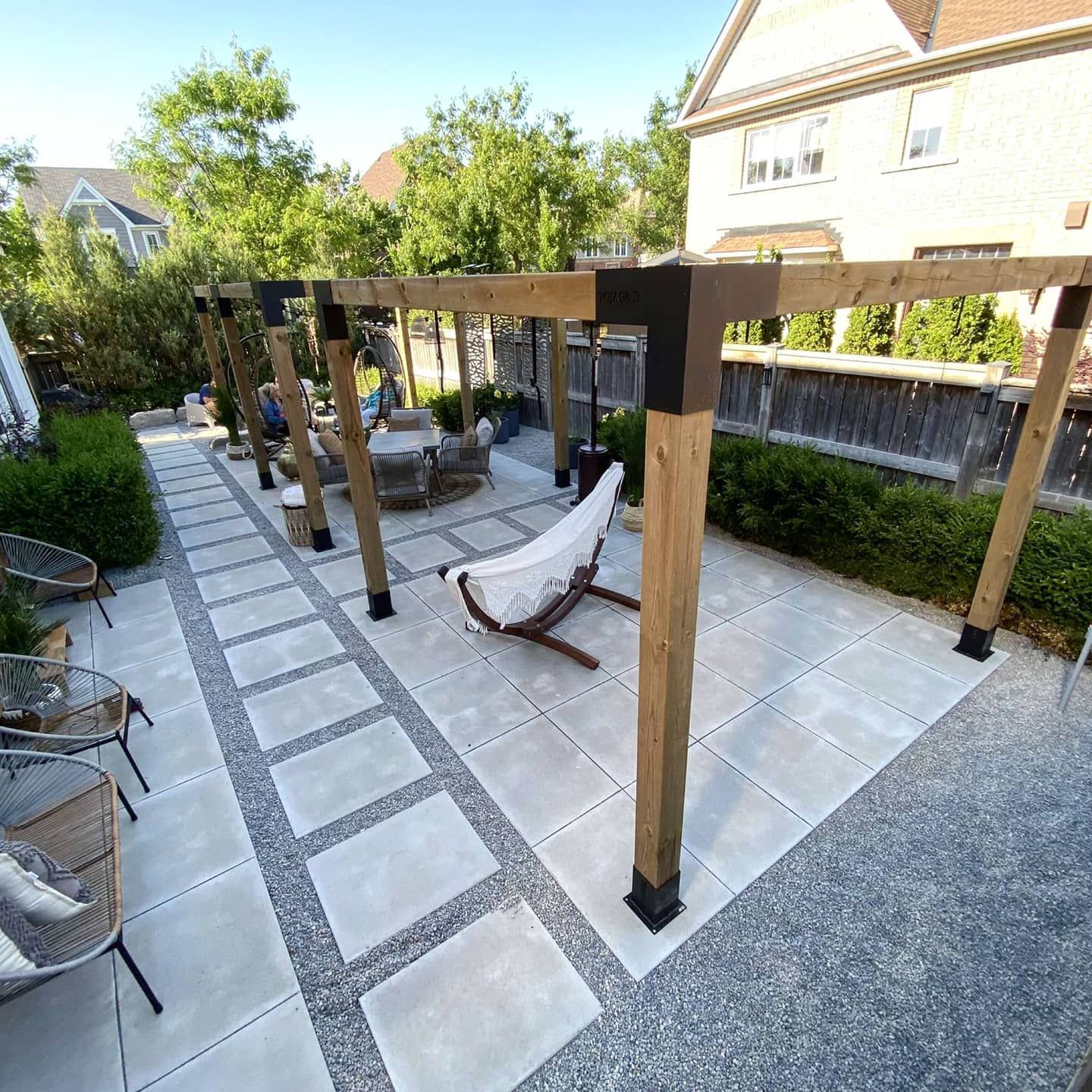 There is a chair under a pergola in the backyard.