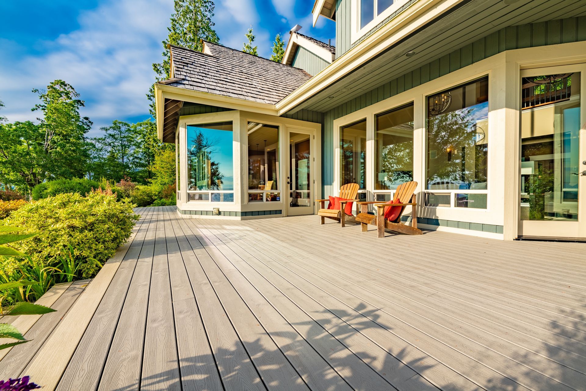A large house with a large deck and chairs on it.