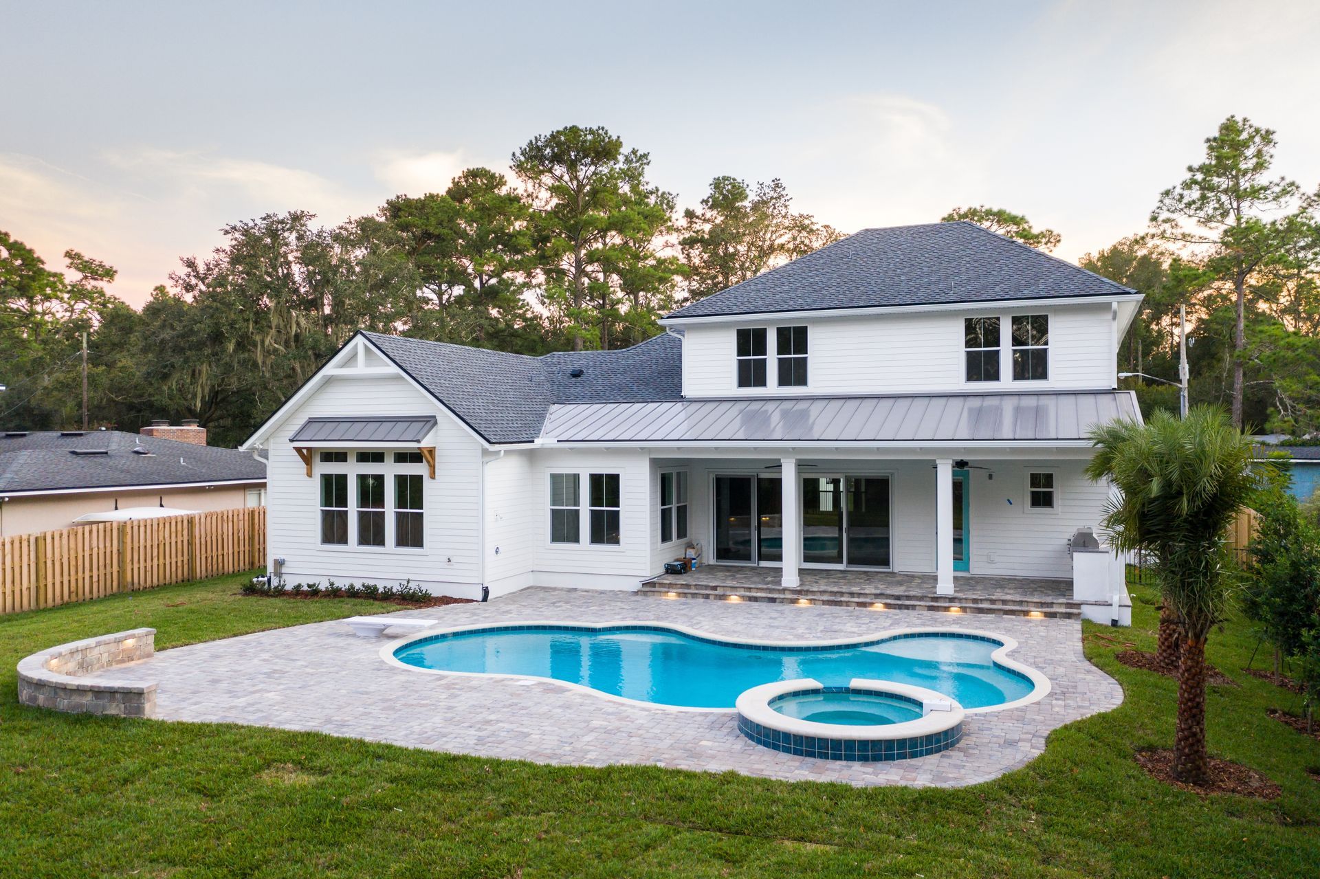 A large swimming pool is surrounded by a white fence