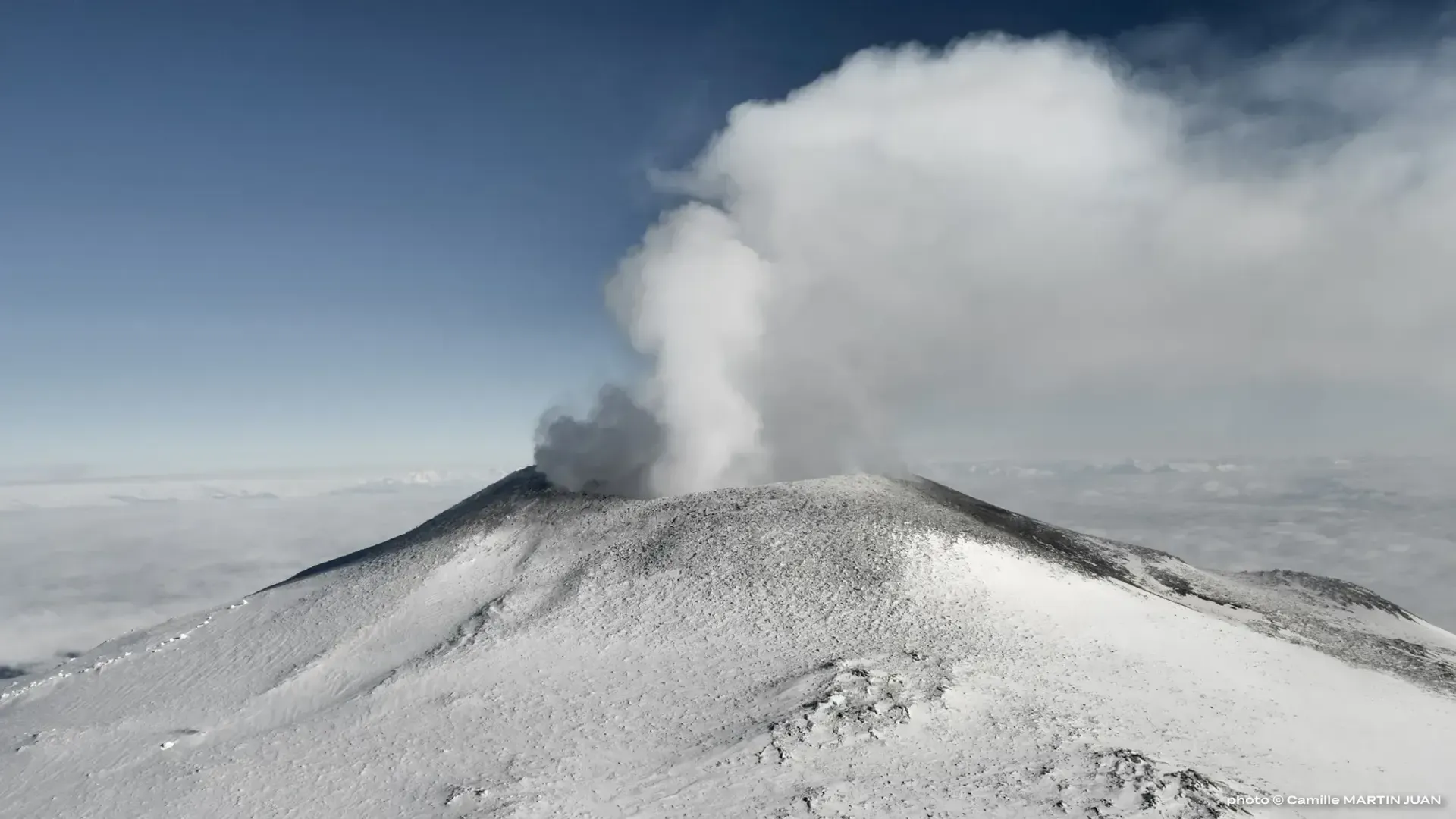 Mount Erebus, Antarctica's only volcanic mountain, venting a large plume of steam into a cloudy sky.