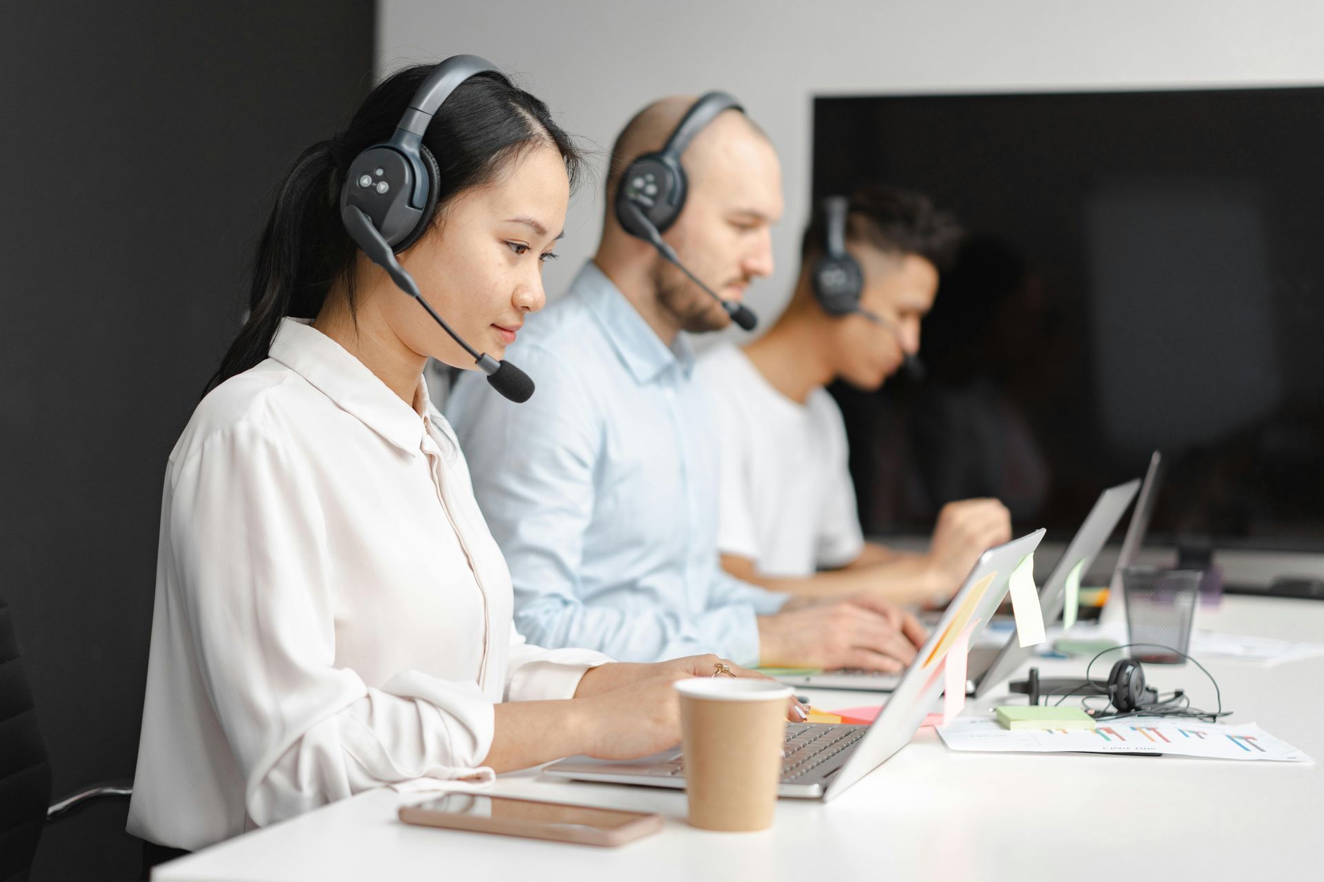 Travel advisors wearing headsets work on laptops to assist customers.