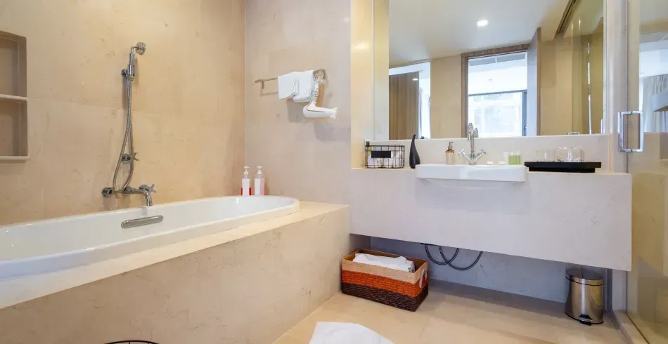 Bright beige bathroom with bathtub, large mirror, and wall-mounted sink vanity