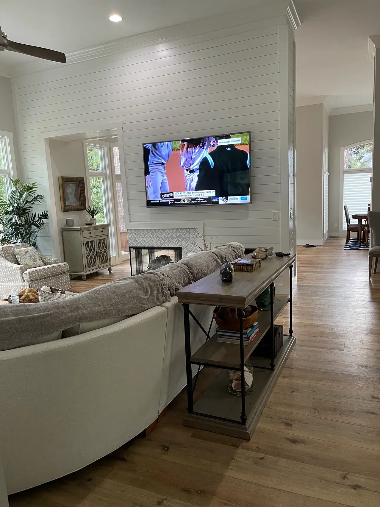 Bright living room with a curved sofa, wall-mounted TV, and patterned white fireplace wall.