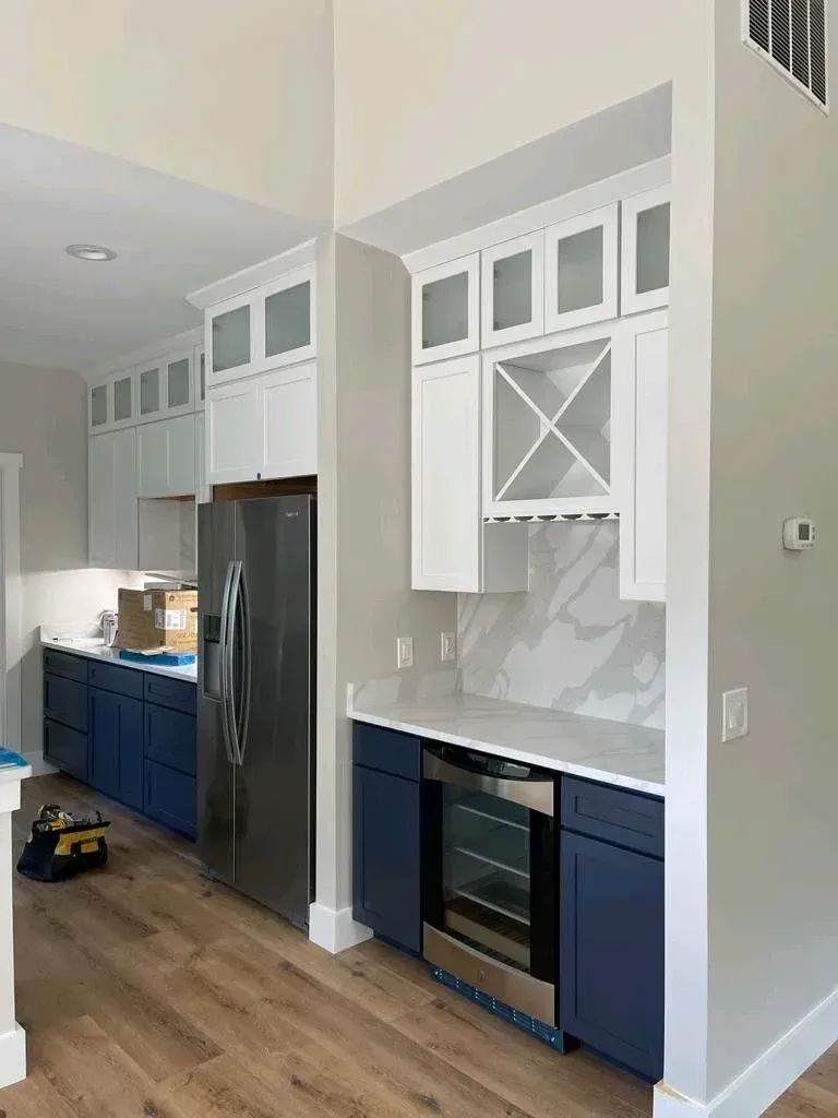 Modern kitchen with blue cabinets, white upper cabinets, and wood flooring