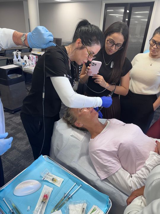An aesthetics teacher showing students an ultrasound procedure.
