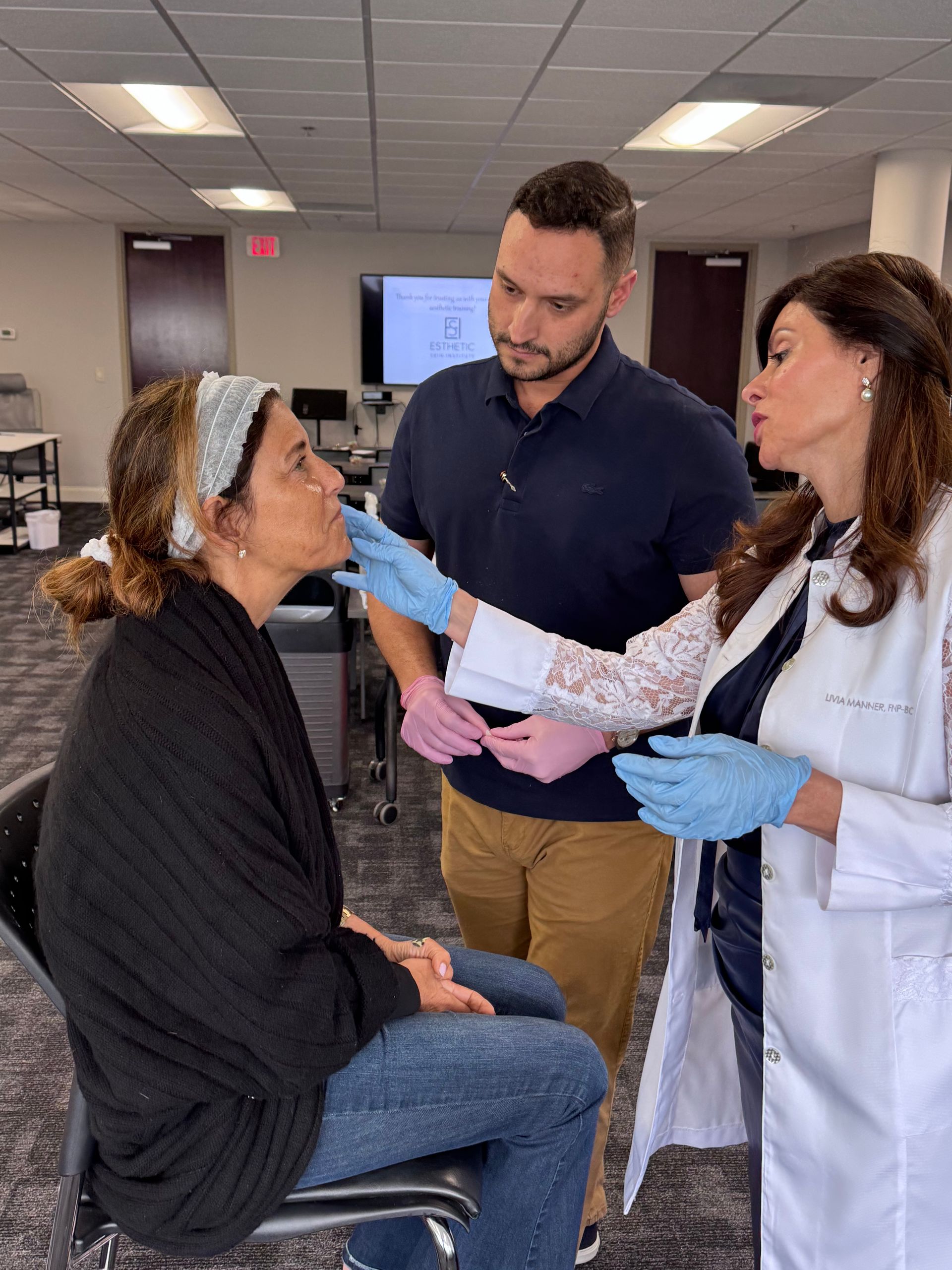 An Esthetic Skin Institute Trainer, showing a medical esthetic student how to assess a patient.