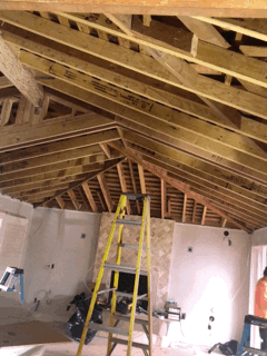 A ladder is sitting in the middle of a room under construction.
