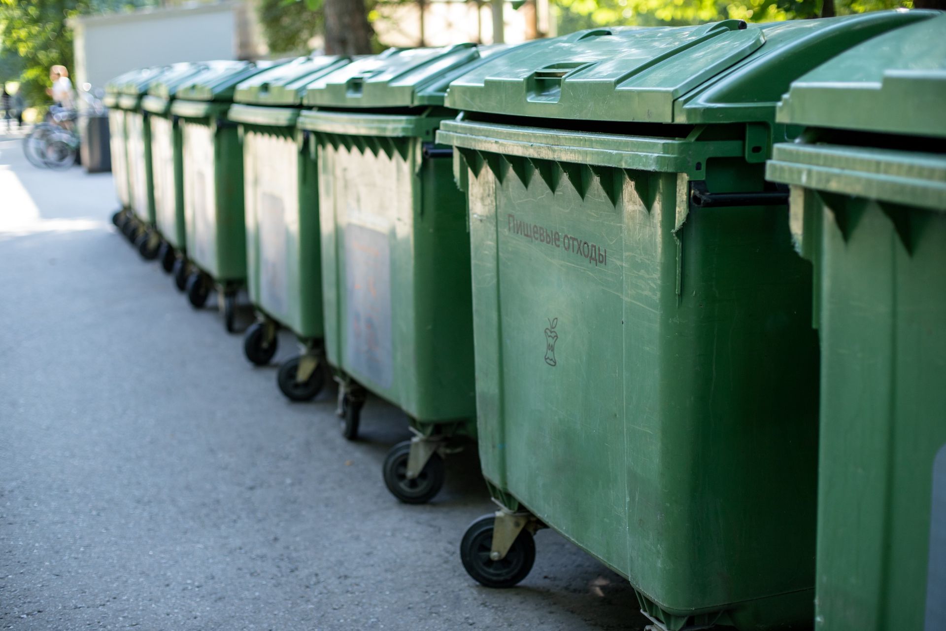 row of 8+ garbage bins on the side of the road with lids closed
