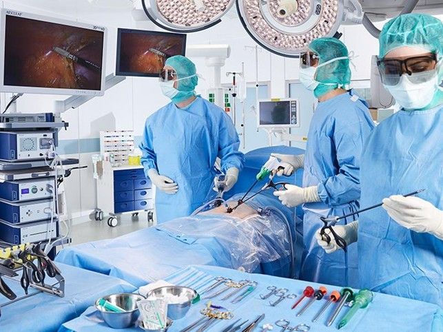 Chirurghi in camice blu che eseguono un intervento in una sala operatoria luminosa